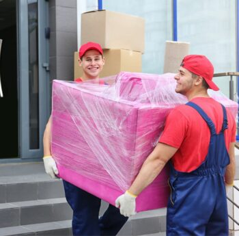 Umzug in Balingen Zwei Umzugshelfer tragen ein in Folie gepacktes Möbelstück – Umzug in Balingen