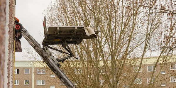 Möbellift zwischen kahlen Bäumen vor einem Gebäude – Möbellift in Balingen