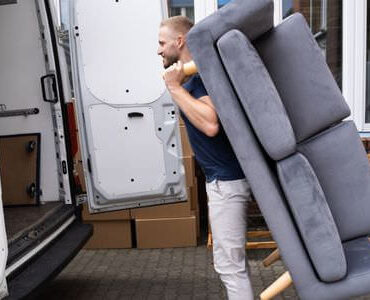 Möbellift Balingen: Helfer tragen ein graues Sofa aus einem Transporter